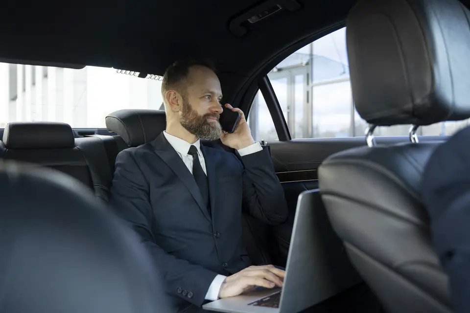 Passenger working in the back seat of a luxury car